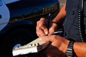 A police office on the side of the road as he writes a ticket.