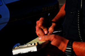 A police office on the side of the road as he writes a ticket.